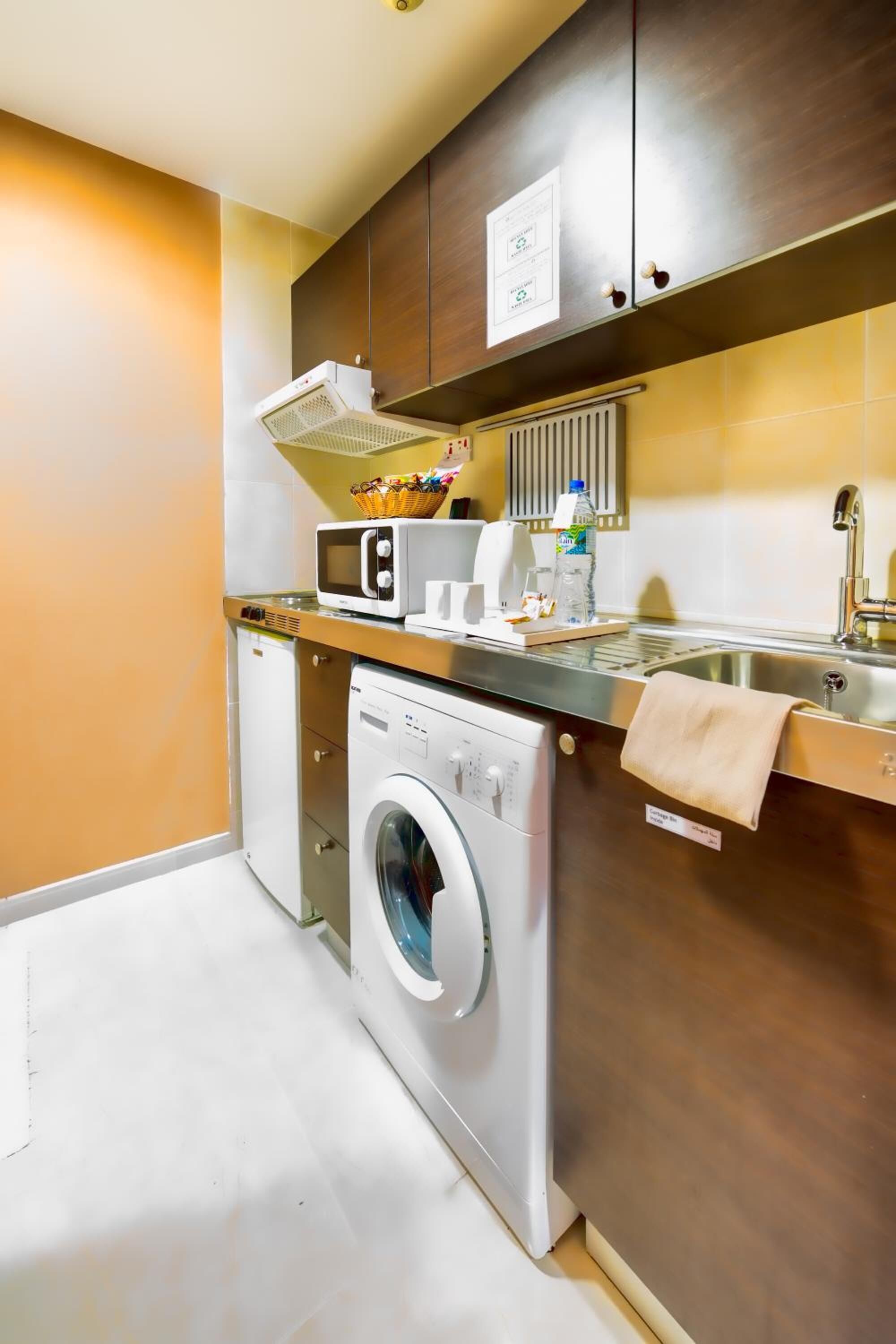 A compact kitchen with a washing machine, microwave, and a small sink.