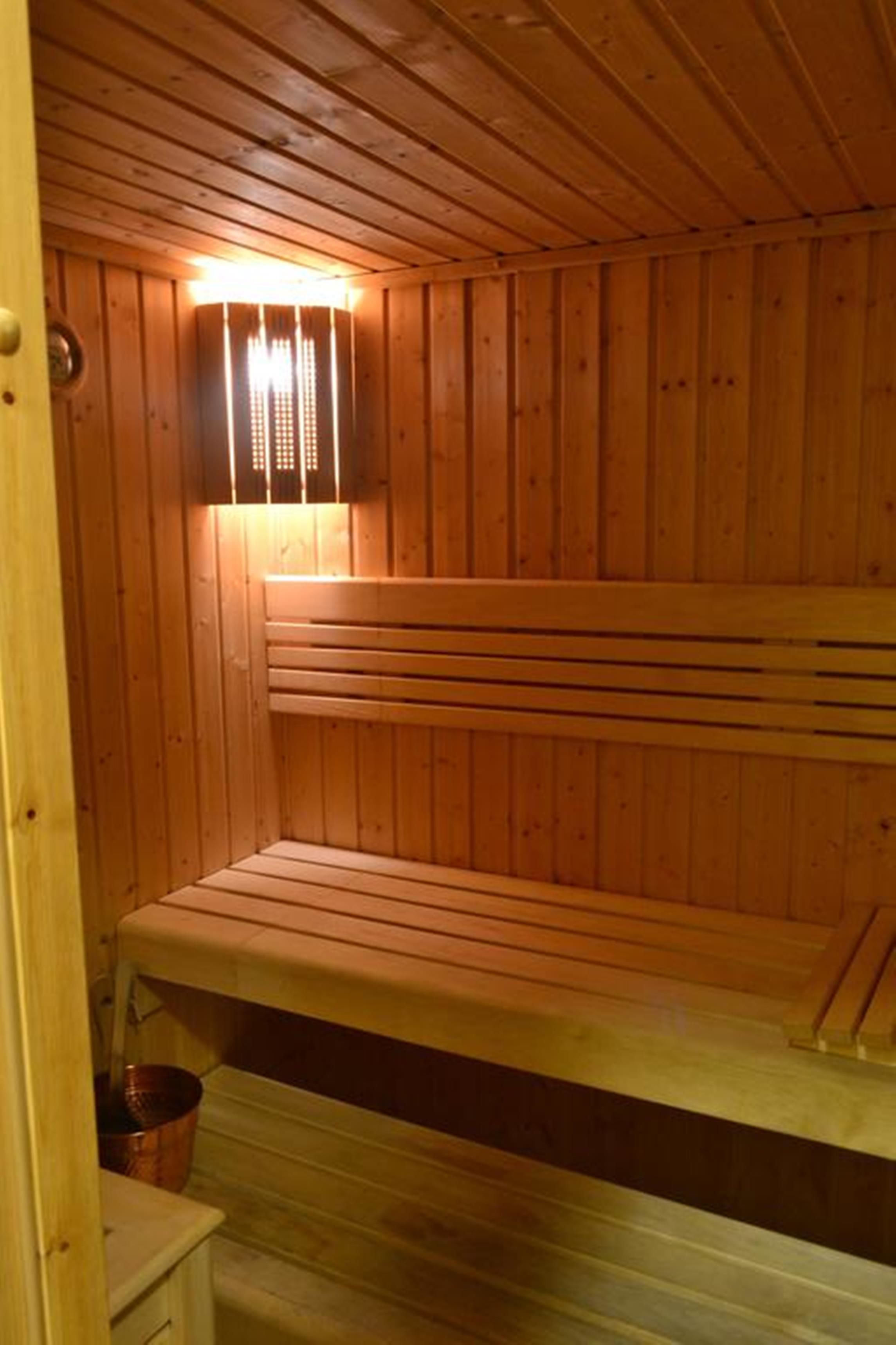A wooden sauna with benches and a window with curtains.
