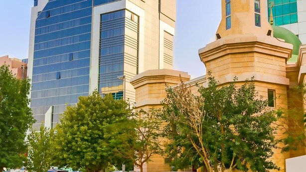 Un edificio moderno con un minarete destacado y fachada de vidrio.