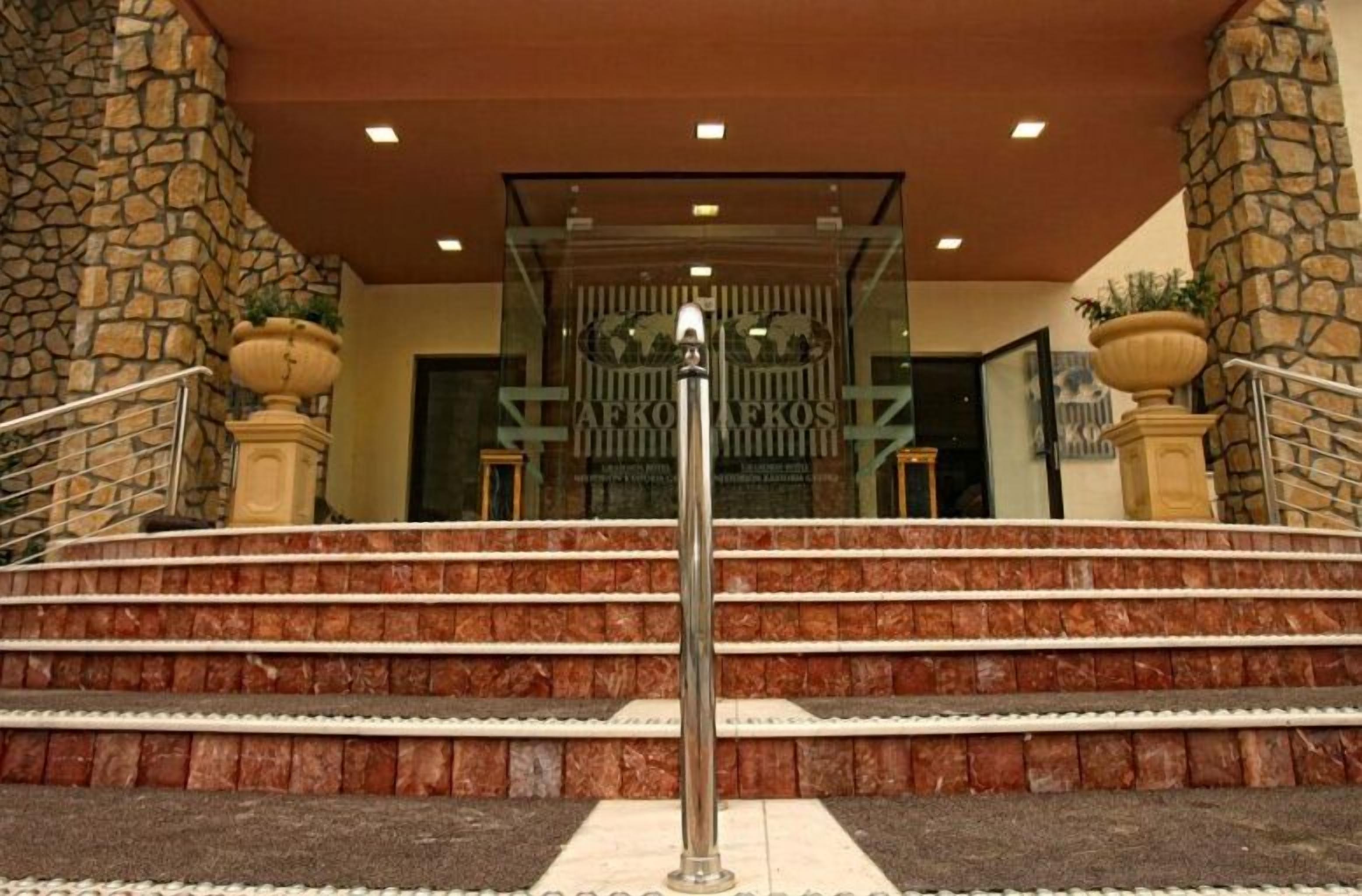 A hotel entrance with stone pillars, a metal railing, and a staircase leading to the entrance.