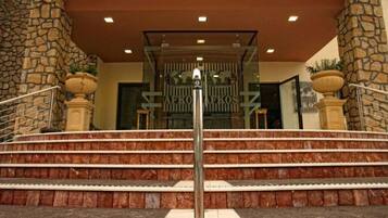 A hotel entrance with stone pillars, a metal railing, and a staircase leading to the entrance.