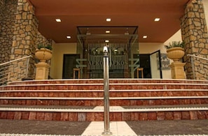 A hotel entrance with stone pillars, a metal railing, and a staircase leading to the entrance. - Afkos Grammos Luxury Boutique Hotel (Nestorio)