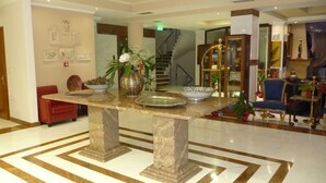 A lobby with a marble floor, a central table with decorative items, and a staircase in the background. - Afkos Grammos Luxury Boutique Hotel (Nestorio)