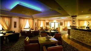 A hotel lobby with a reception desk, seating area with tables and chairs, and a patterned carpet. - Afkos Grammos Luxury Boutique Hotel (Nestorio)