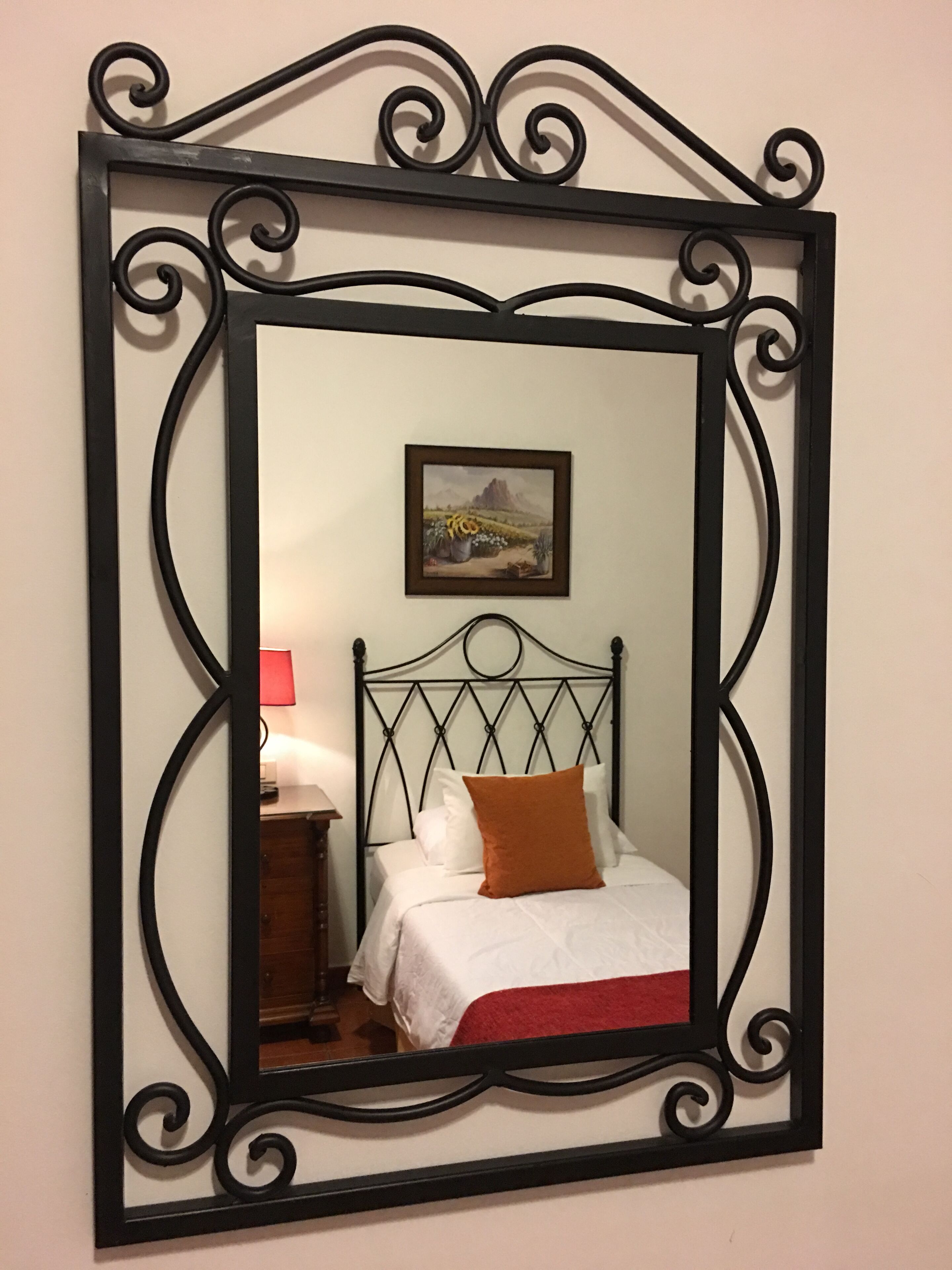 Un dormitorio con cama, mesita de noche, lámpara y un cuadro en la pared.