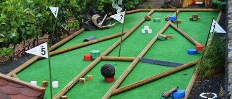 A miniature golf course with numbered holes, obstacles, and a green artificial turf surface.
