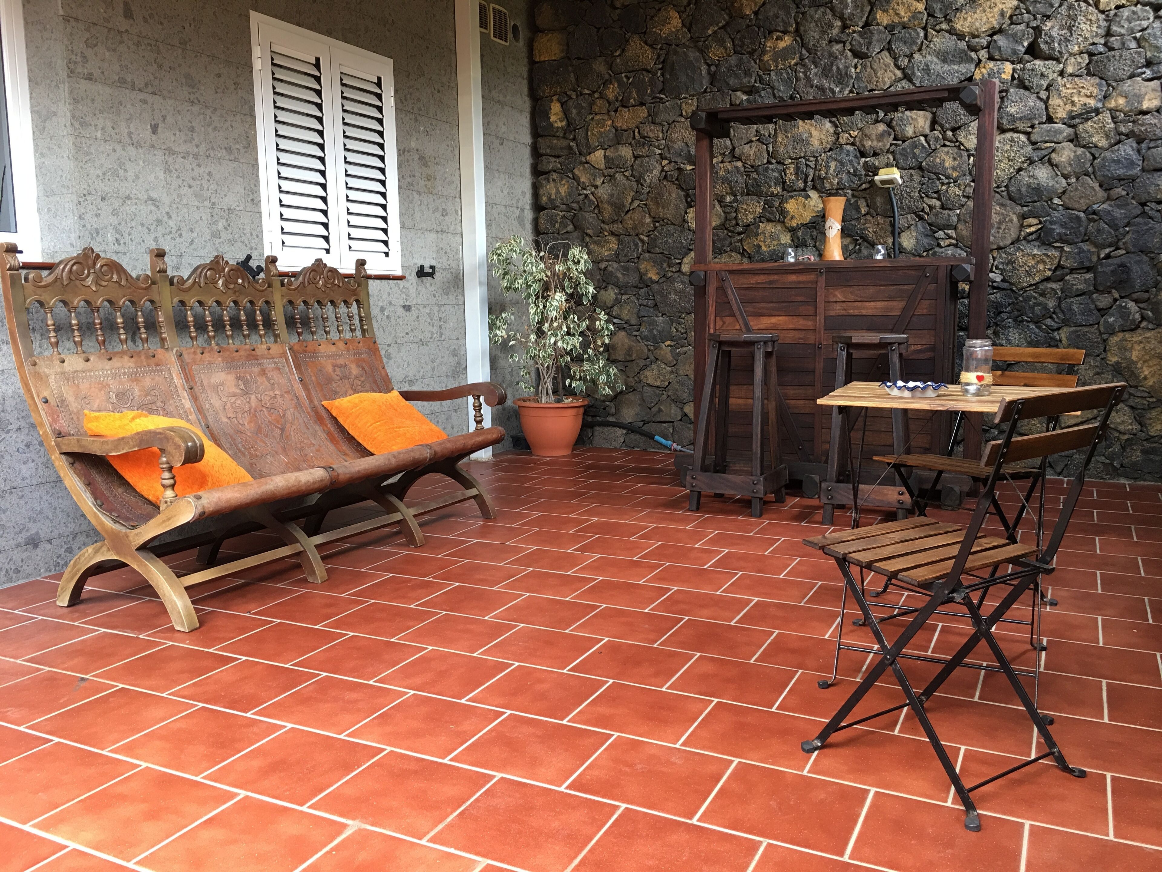 Une terrasse avec un banc en bois, une table et des chaises.