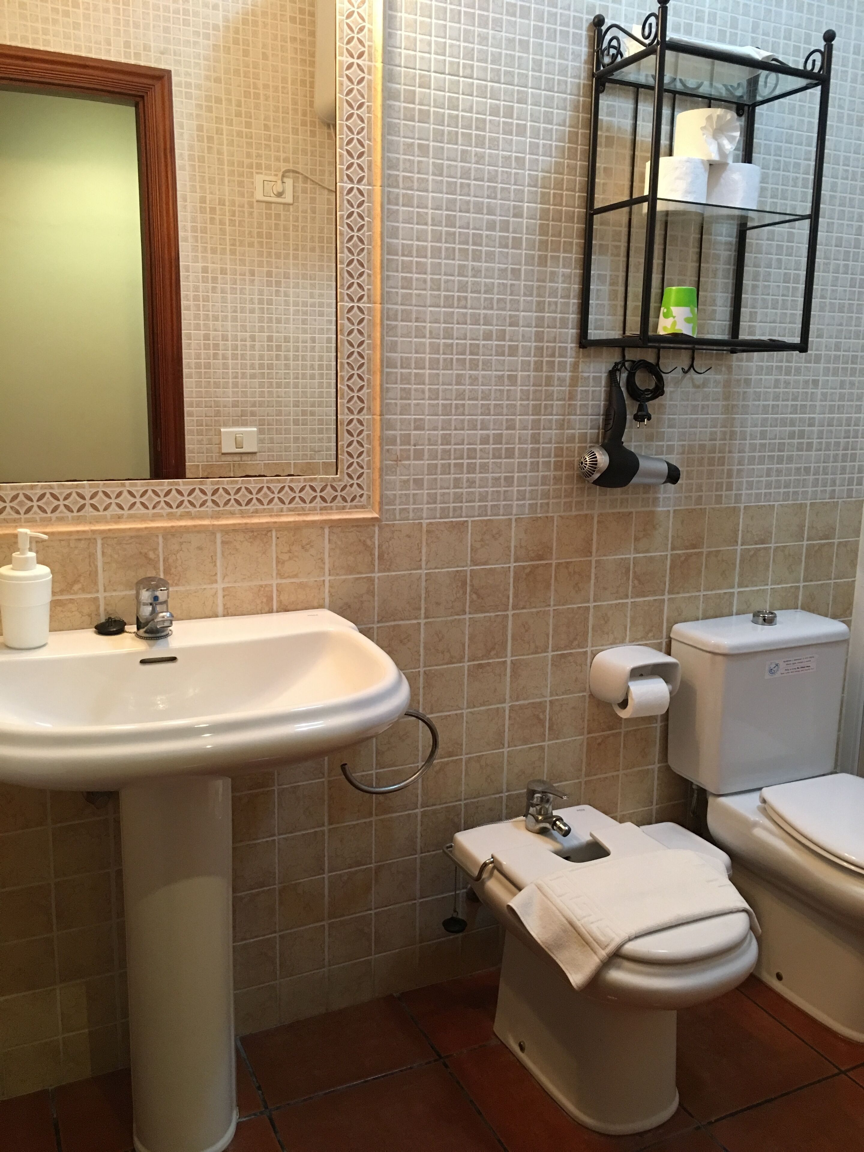A bathroom with a sink, toilet, and a mirror.
