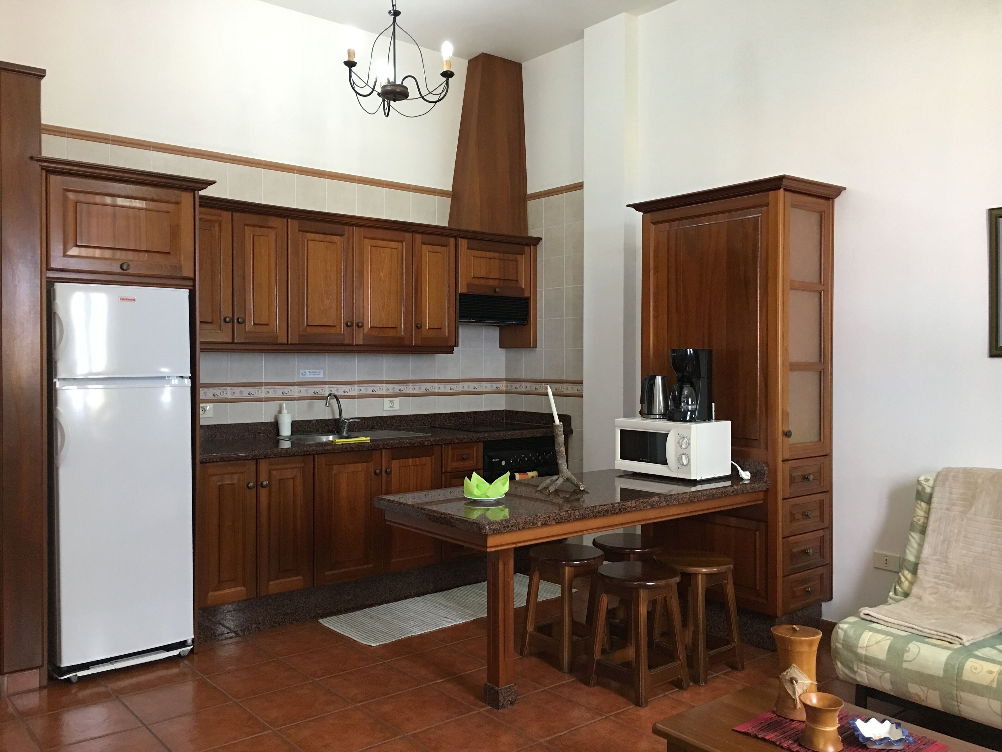 A kitchen with wooden cabinets, a refrigerator, a microwave, and a coffee maker.