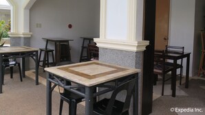 A dining area with tables and chairs, a door, and a wall with two red circular decorations. - Villa del Pueblo (Panglao)