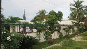 A residential area with a for sale sign, lush greenery, and a white building. - Villa del Pueblo (Panglao)