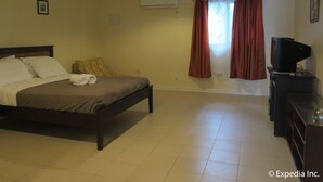 A hotel room with a bed, a TV, and a window with curtains. - Villa del Pueblo (Panglao)