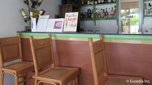 A bar area with wicker chairs, a menu board, and shelves stocked with liquor bottles. - Villa del Pueblo (Panglao)