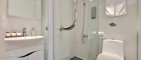 A modern bathroom with a glass-enclosed shower, a white sink with a mirror above it, and a toilet.