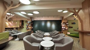 A modern interior with round tables and chairs, wooden accents, and a chalkboard wall. - Green Hotel - Fengjia (Taichung)