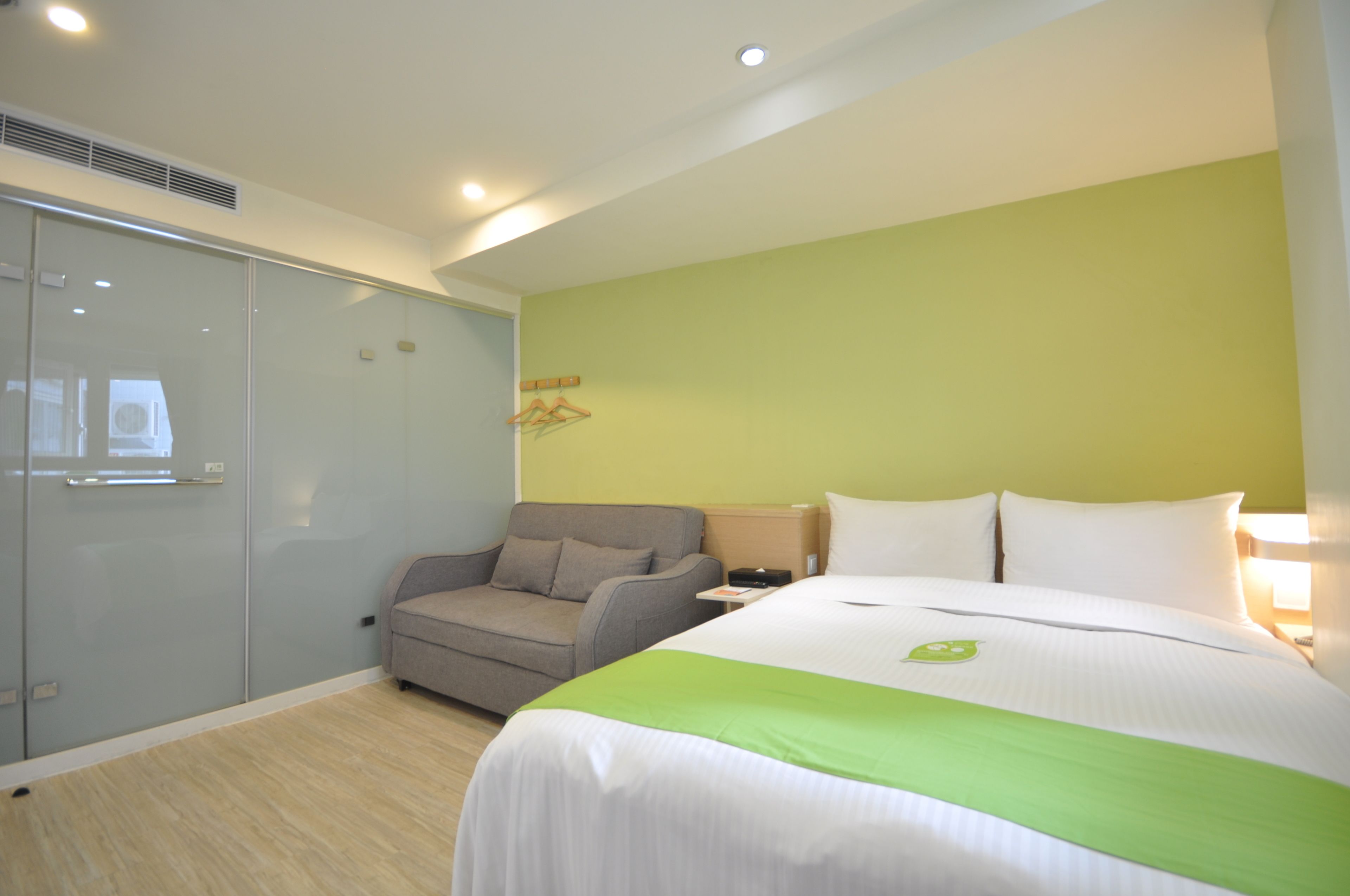 Une chambre d’hôtel comprenant un lit, un canapé, une table de chevet et une armoire.