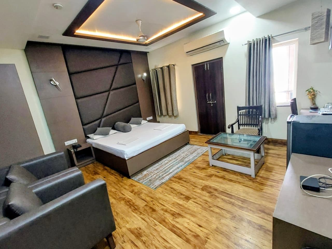 A modern bedroom with a bed, a glass coffee table, and a seating area with chairs.