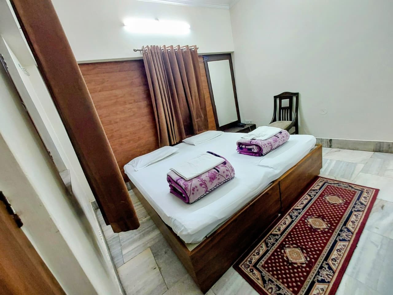 A bedroom with a bed, a nightstand, a mirror, and a door.