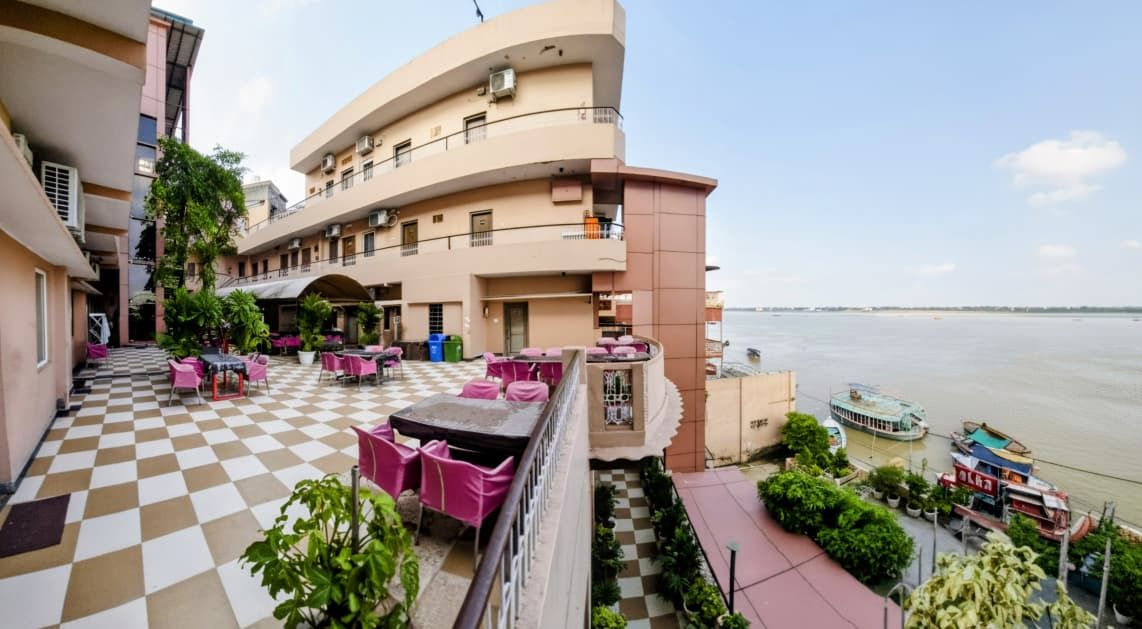 A hotel with a checkered floor, outdoor seating, and a view of a river.