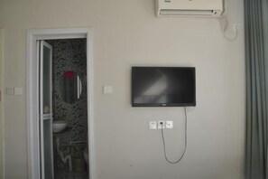 A bathroom with a toilet, sink, and shower. There is a flat-screen TV mounted on the wall and a power outlet below it. - Aike 100 Theme Hotel (Qingdao Chongqing North Road Liuting Subway Station) (Qingdao)