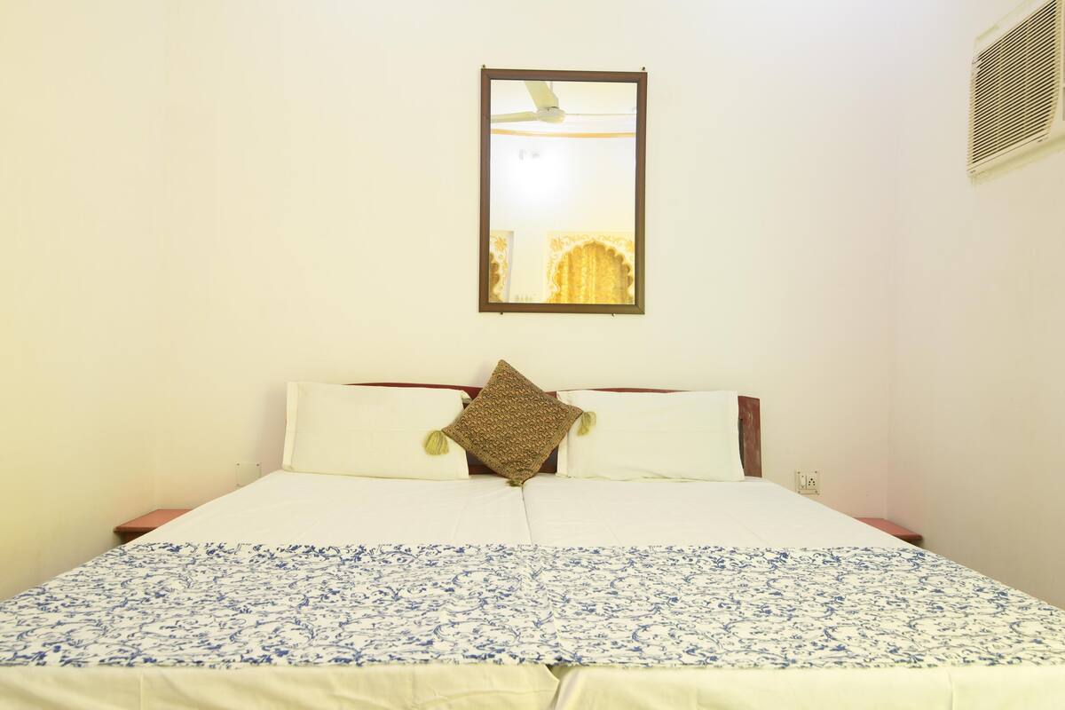 A neatly made bed with a patterned bedspread, a single decorative pillow, and a framed picture on the wall above.