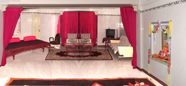 Una habitación con cama, sofá, televisión y un espejo decorativo.
