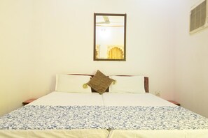 Una cama con una colcha estampada, dos almohadas y un cuadro en la pared.