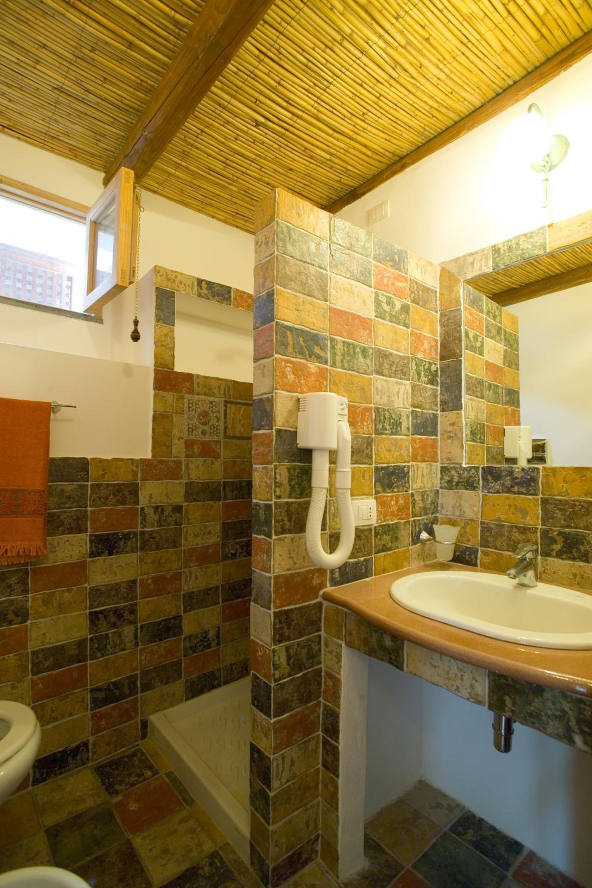 Un baño con ducha azulejada, lavabo e inodoro.