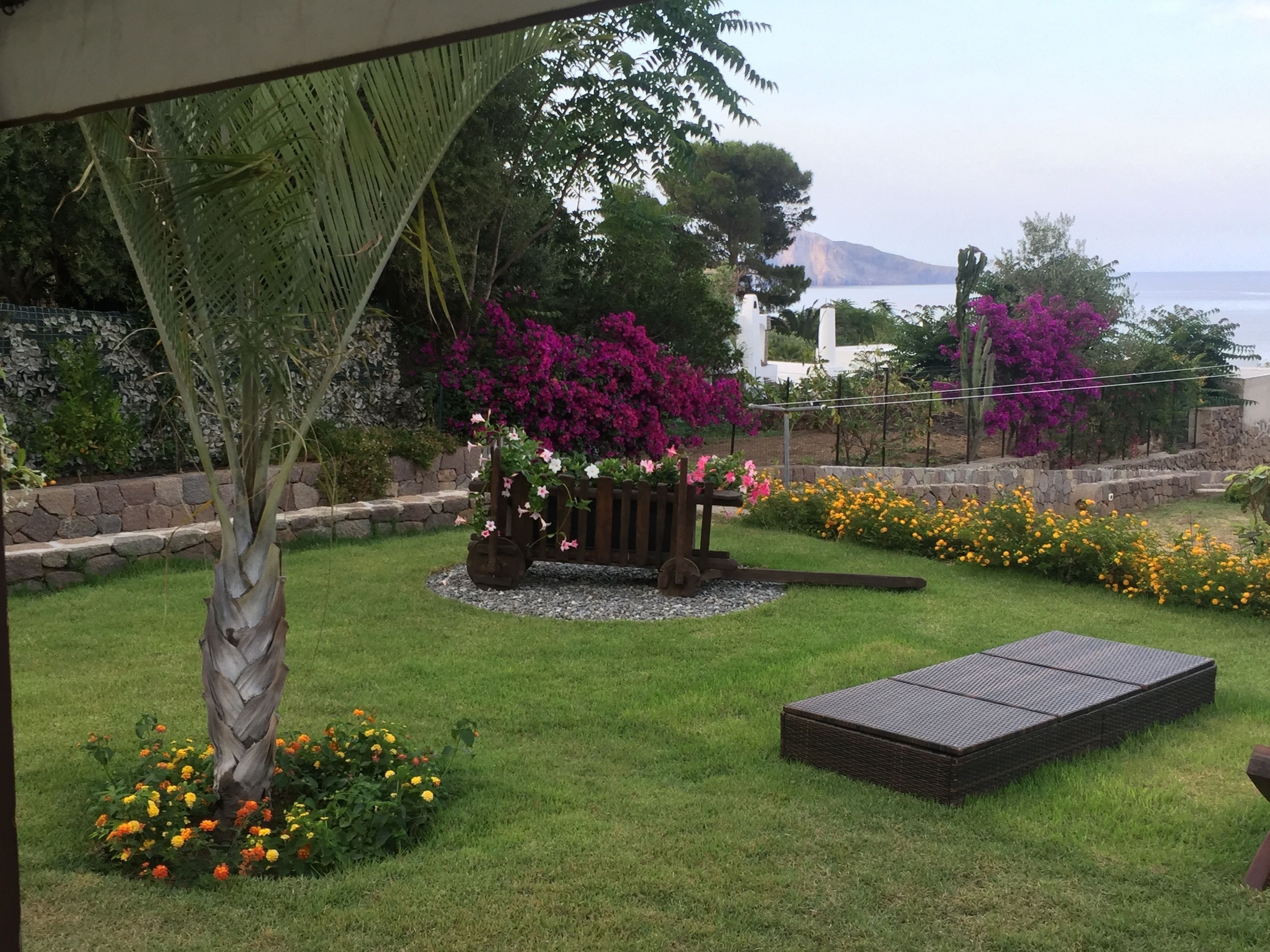 A garden with a wooden bench, a small table, and a variety of flowers.