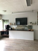 Moderni keittiö, jossa on tasokiinnitteinen litteänäyttöinen televisio, kahvinkeitin ja pieni jääkaappi.
