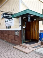 Rakennuksessa on kyltti, jossa lukee »Hostel River», sen julkisivu on tehty tiilestä ja siinä on puinen sisäänkäynti.