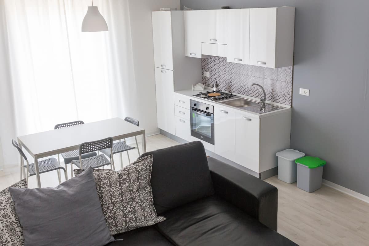 Une cuisine de taille réduite avec des meubles blancs, une cuisinière à gaz et un évier.