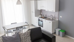 Une cuisine de taille réduite avec des meubles blancs, une cuisinière à gaz et un évier.