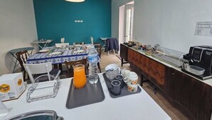 Une table préparée pour le petit-déjeuner, avec des chaises, une machine à café et une horloge au mur.