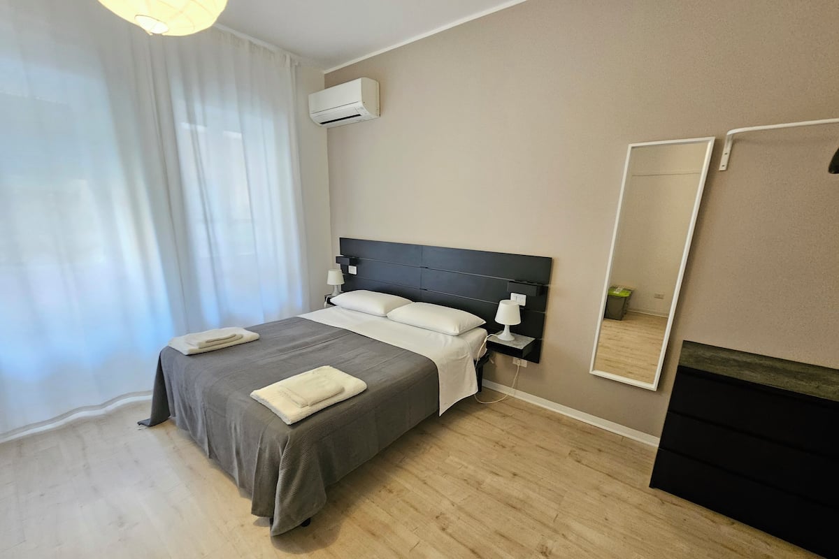 Une chambre d’hôtel moderne équipée d’un lit, de lampes de chevet, d’un miroir et d’un appareil de climatisation.
