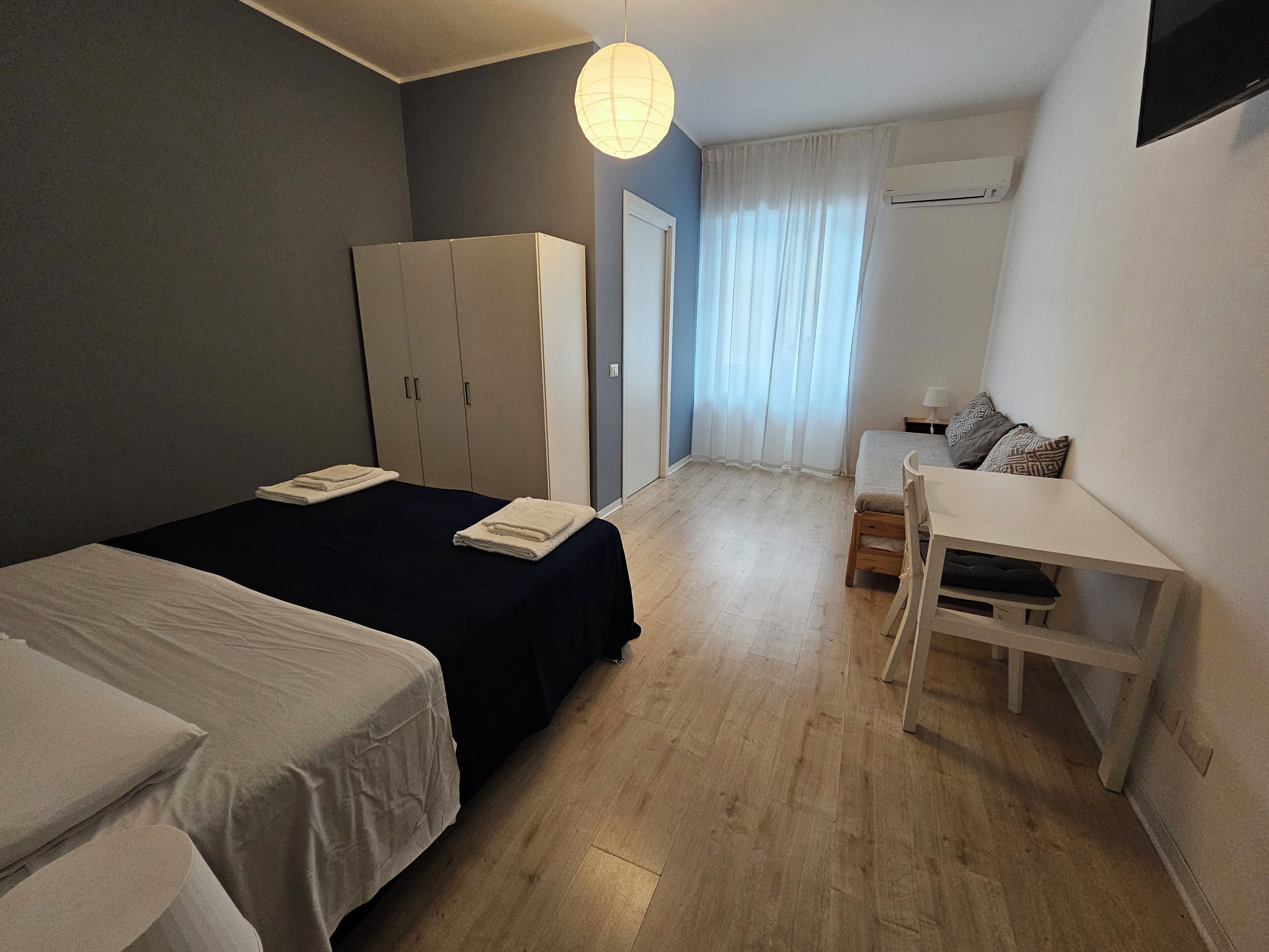 Ein Schlafzimmer mit zwei Betten, einem Schreibtisch und einem Kleiderschrank.