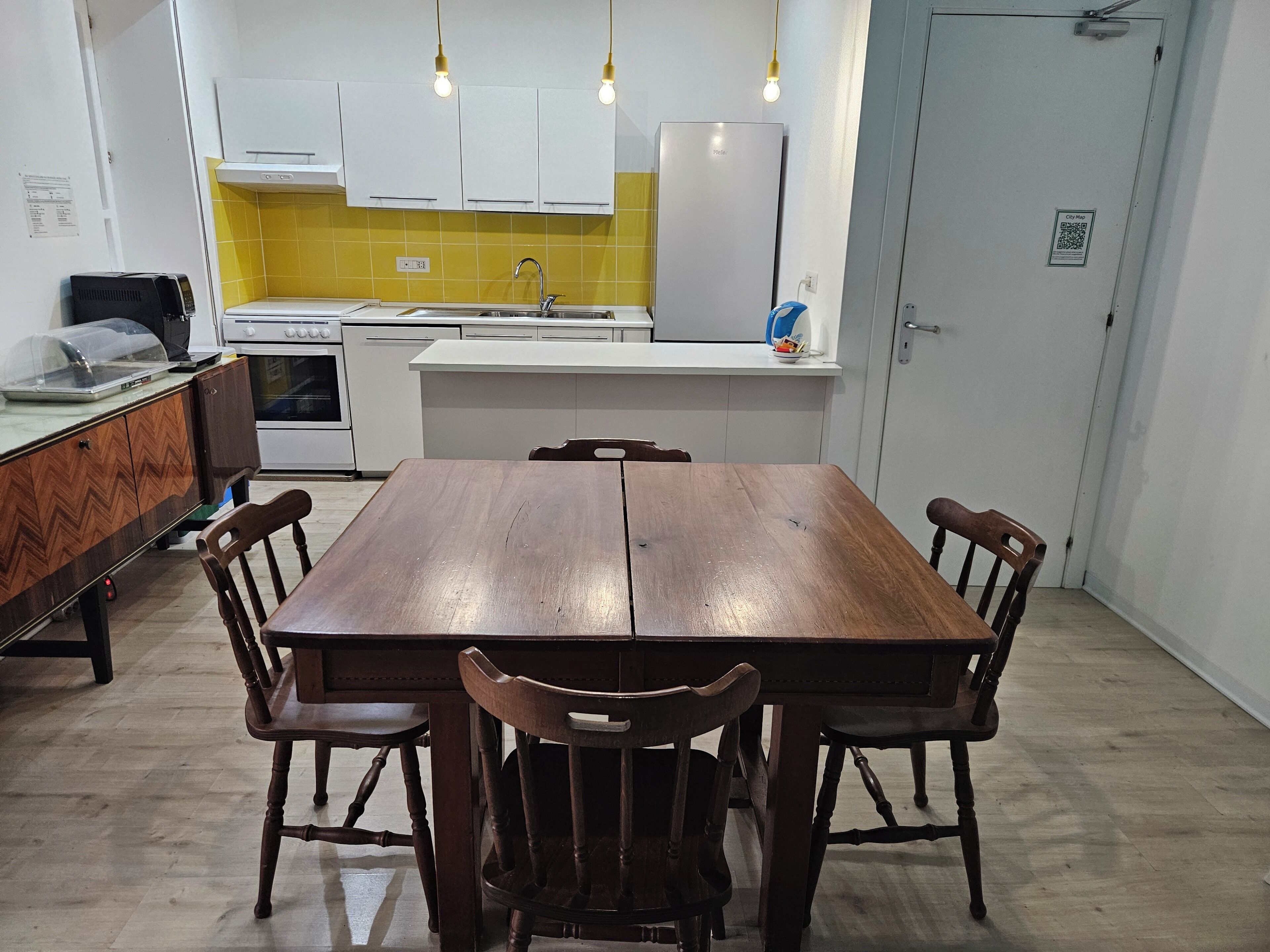 Cozinha moderna com armários brancos, painel de parede amarelo e forno embutido.