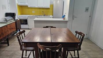 Cozinha moderna com armários brancos, painel de parede amarelo e forno embutido.