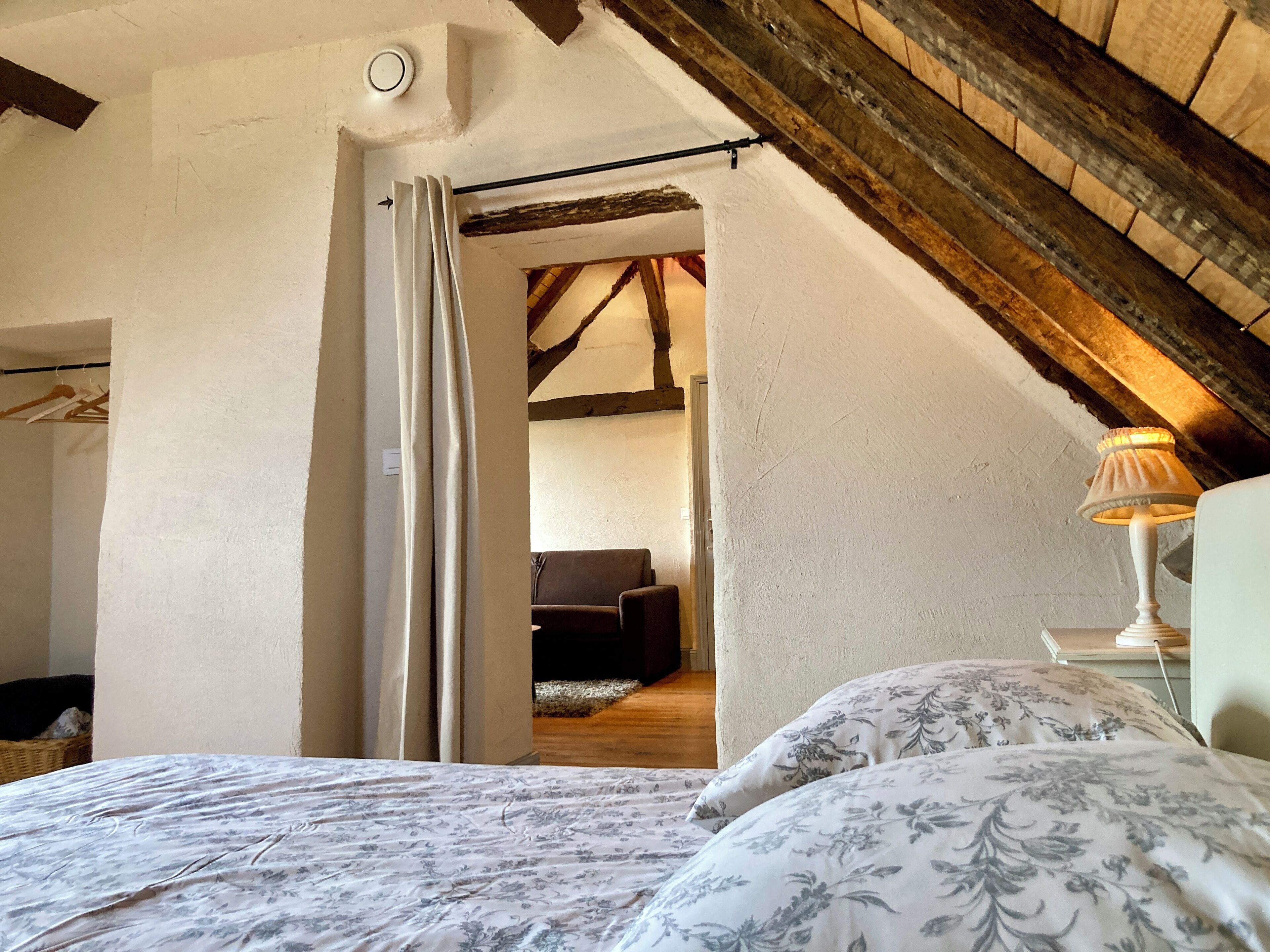 A bedroom with a bed, a nightstand, a lamp, and a wooden ceiling.