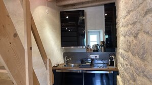 A compact kitchen with a wooden beam structure, a built-in stove, and a sink. - Domaine du Moulin de Champie – Plaine de Versailles (Davron)