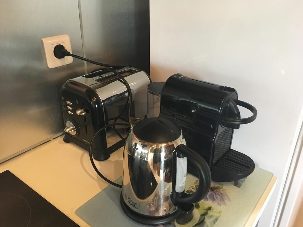 A kitchen area with a toaster, a coffee maker, and a kettle on a countertop.