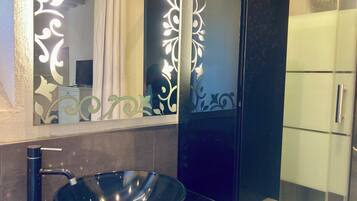 Une salle de bain moderne avec un lavabo sur pied noir, un miroir orné de motifs décoratifs et une douche à parois de verre.