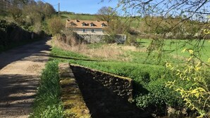 A rural road leading to a stone house with a tiled roof. - Domaine du Moulin de Champie – Plaine de Versailles (Davron)