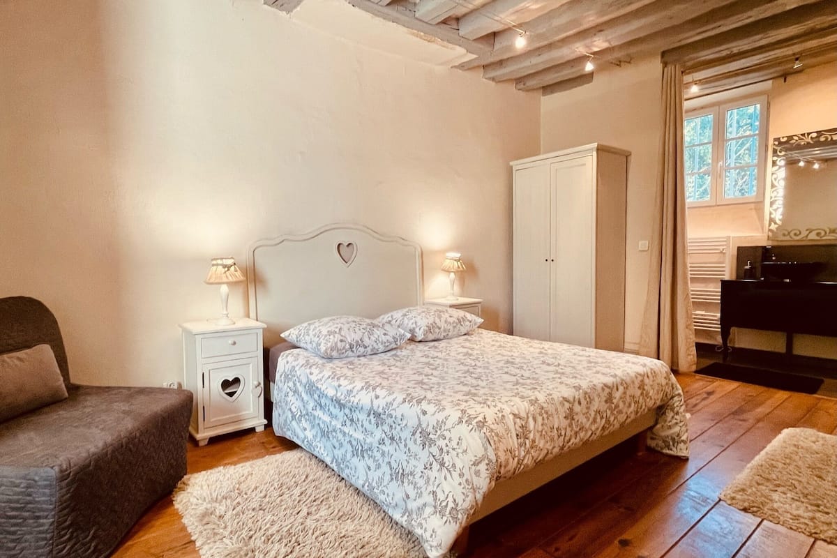 A bedroom with a bed, nightstands, a wardrobe, a chair, and a window.