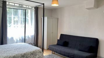 Een slaapkamer met een bed, een bank, een kledingkast en een raam met gordijnen.
