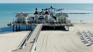 A pier with a white building featuring large windows and a dome, extending into the sea.
