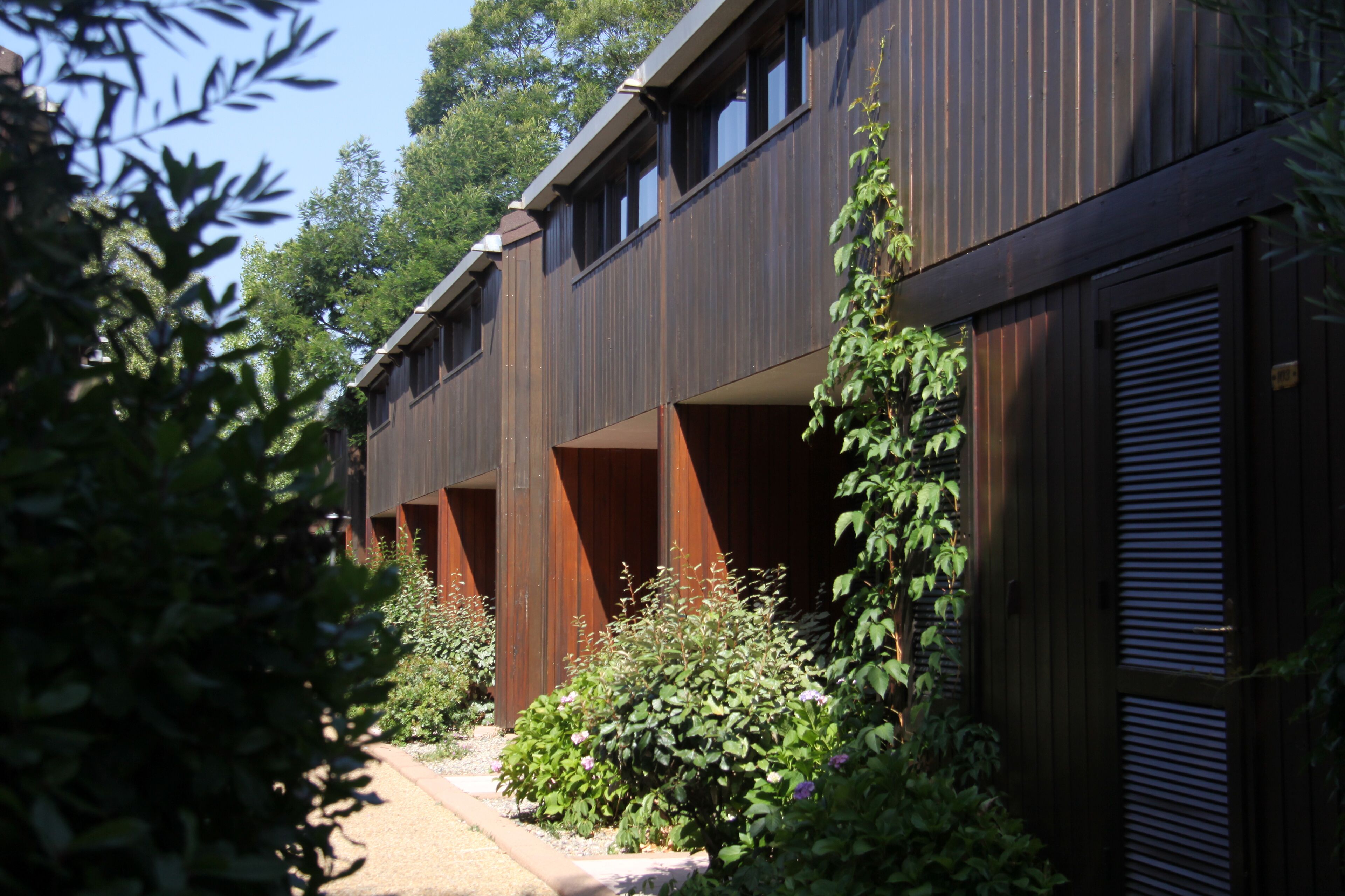 A modern building with multiple balconies and a garden area.