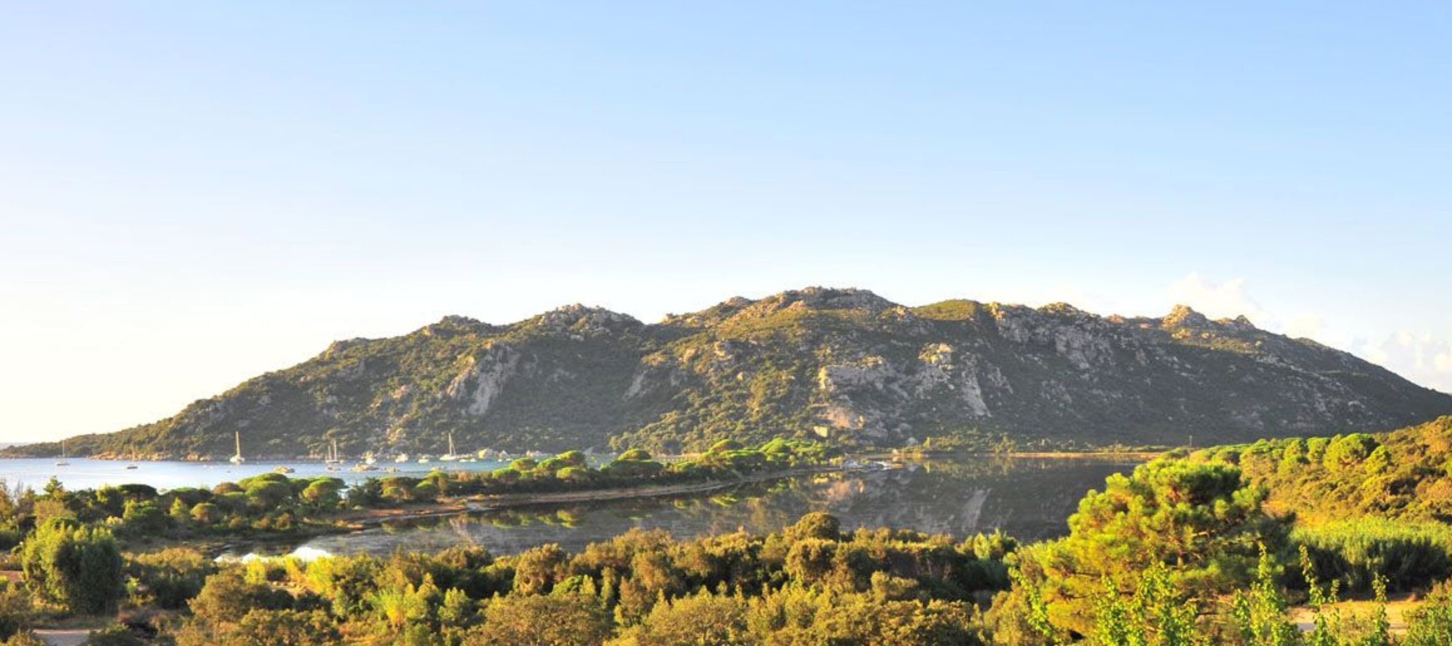 A mountainous landscape with a body of water in the foreground and a clear sky.