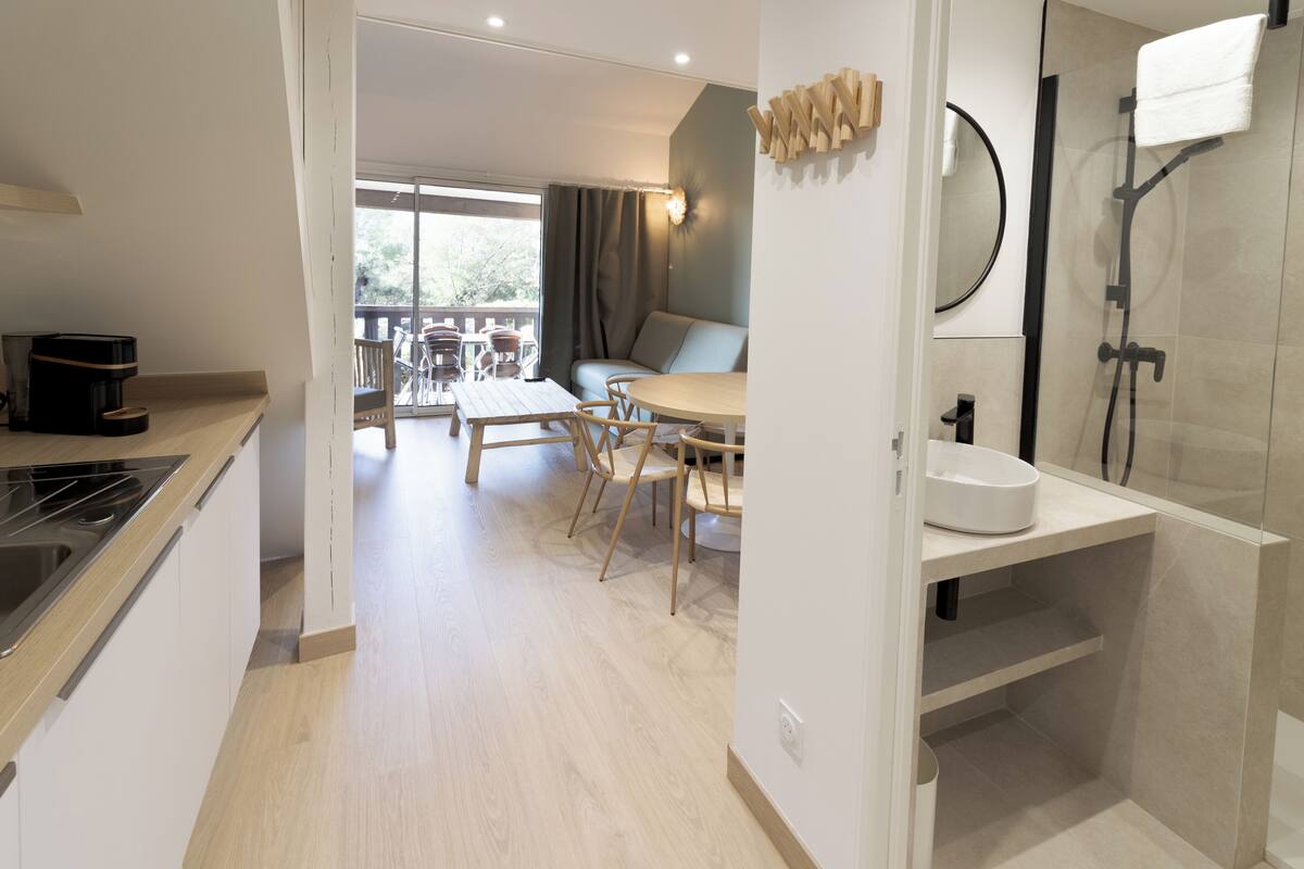 A modern kitchen with a dining area, a balcony, and a shower area.