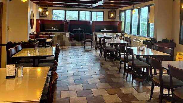 Un restaurant doté de nombreuses tables et de banquettes, de grandes fenêtres et d’un sol carrelé.